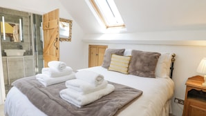 A bedroom with a large bed, two pillows, a bedside table, and a skylight. - Pentre Hall (Oswestry)