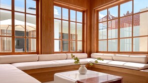 A modern living room with a large sectional sofa, a wooden coffee table, and large windows offering a view of a traditional building. - Tekko Villa Pererenan (Canggu)
