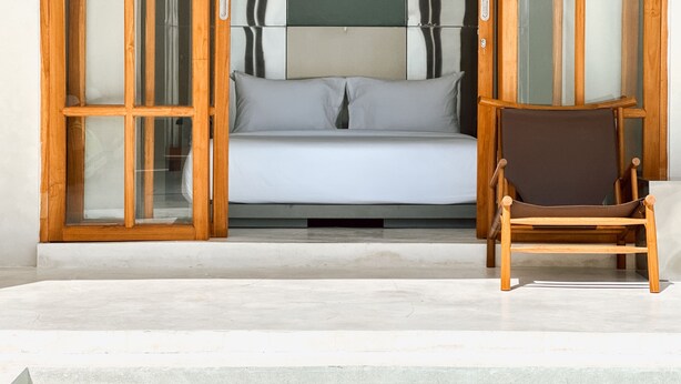 A room with a bed, a chair, and a glass door leading to a balcony. - Tekko Villa Pererenan (Canggu)