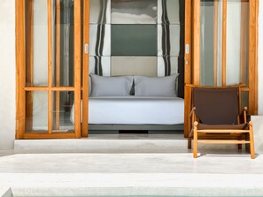 A room with a bed, a chair, and a glass door leading to a balcony. - Tekko Villa Pererenan (Canggu)