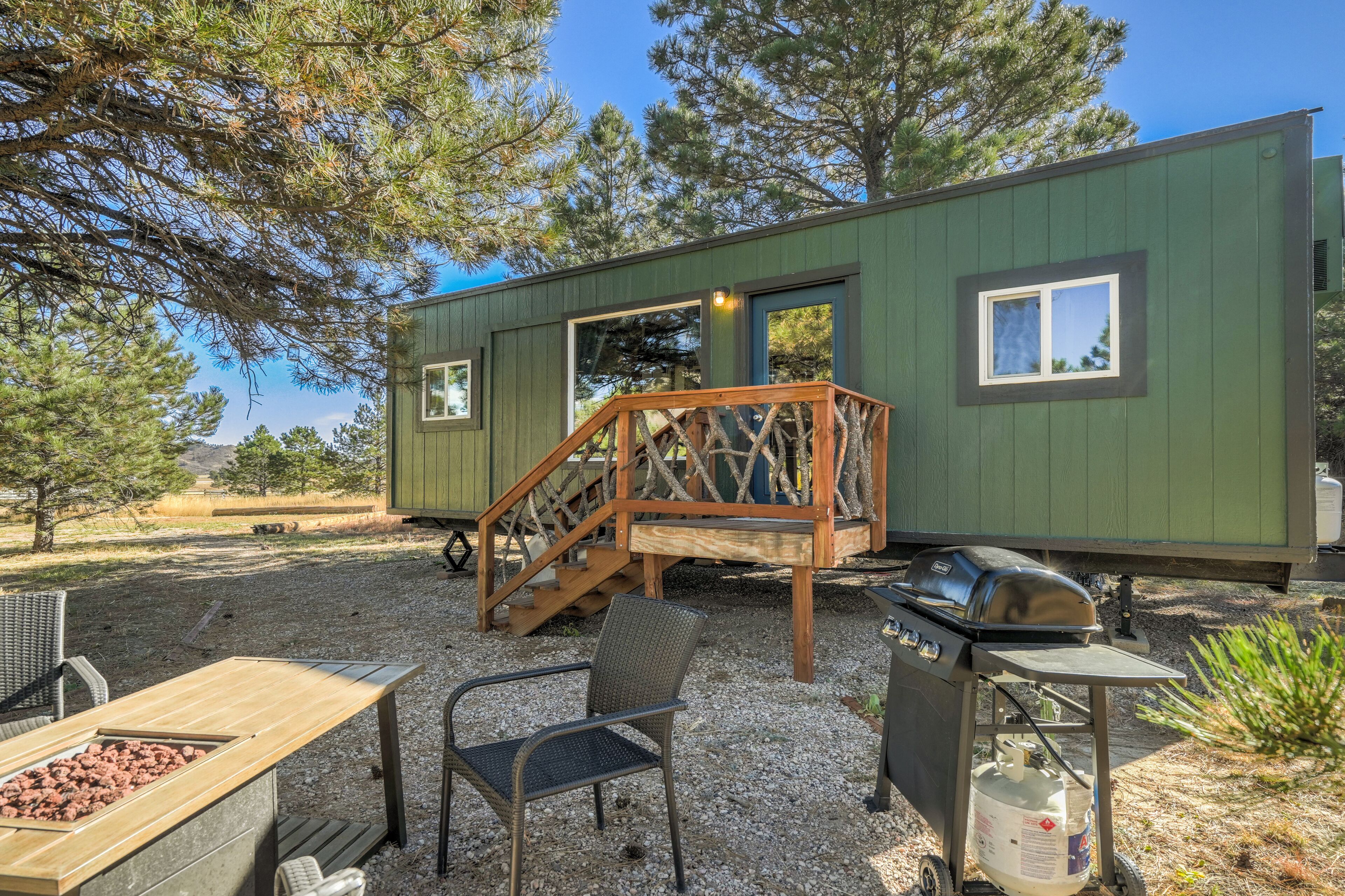 A small cabin with a wooden deck, a grill, and outdoor seating.