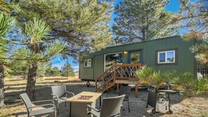 Une cabane dotée d’une terrasse, de meubles de jardin et d’un foyer extérieur.