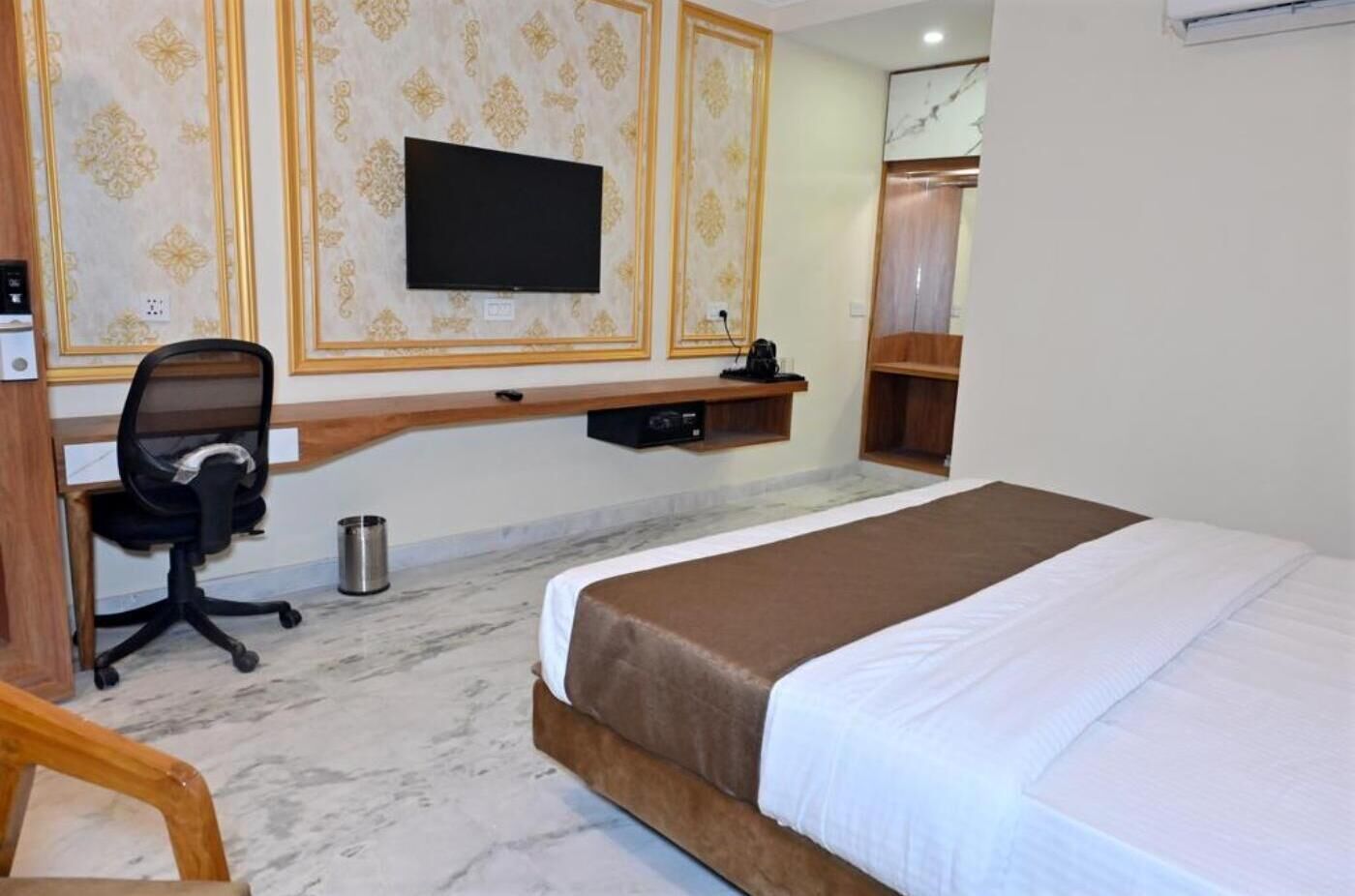Une chambre d’hôtel équipée d’un lit, d’un bureau, d’une chaise, d’une télévision et d’une armoire.