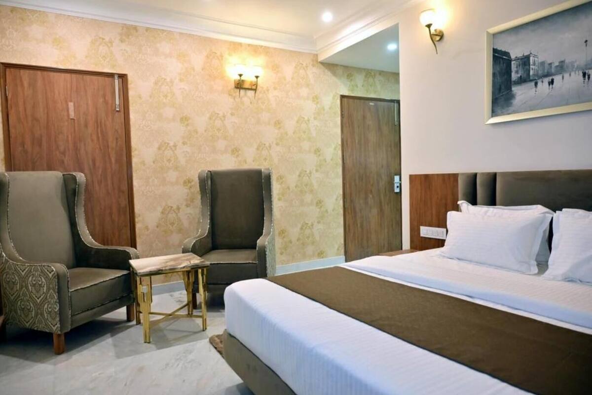Een hotelkamer met een bed, twee fauteuils, een tafeltje en een schilderij aan de muur.