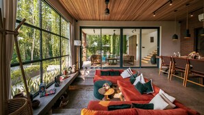 Un interior moderno con un ventanal grande, techo de madera y una zona de estar con sofá y mesa.