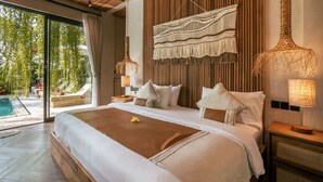 Una cama grande con cabecera de madera, un tapiz de macramé y vistas a una piscina a través de amplias puertas de cristal.