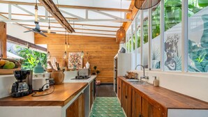 A modern kitchen with wooden cabinets, a green patterned floor, and large windows with tropical views. - Private Pool • Hot Tub • Near Batu Bolong Beach (Canggu)
