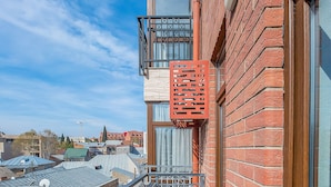 Un balcone con un tavolo di legno e due tazze, un muro di mattoni rossi e vista sulla città.