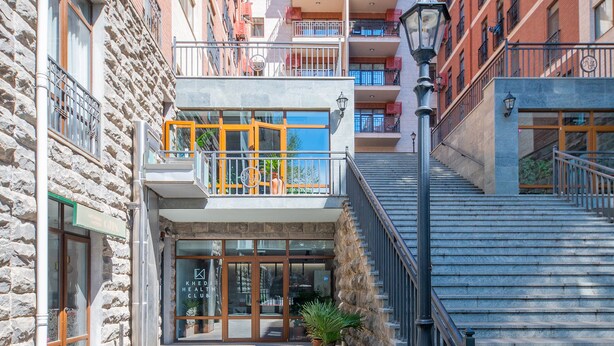 Un cortile con un edificio in pietra, un ingresso in vetro e una scala che conduce ai piani superiori.