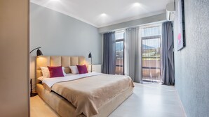 Una camera da letto moderna con un letto grande, un comodino e vista sull'esterno tramite una porta scorrevole in vetro.