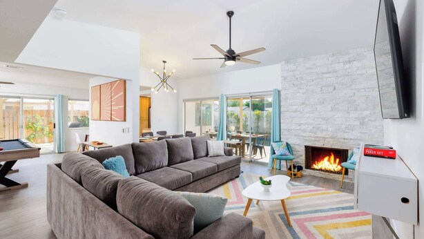 A modern living room with a sectional sofa, a pool table, a fireplace, and a television. - SoCal Private Pool Bungalow |4BR (Indio)