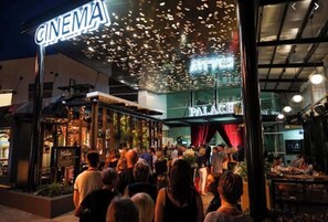 Un cine con un cartel luminoso y una multitud de personas afuera.