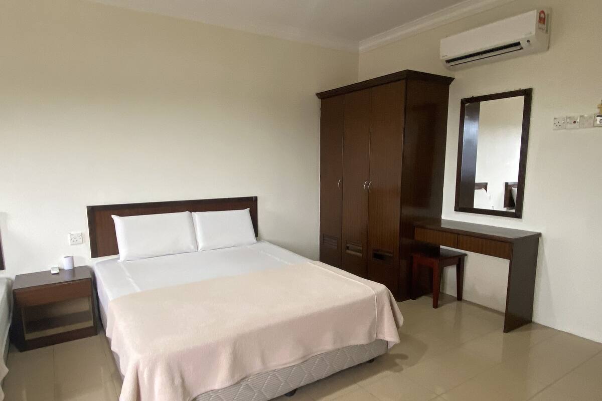 Une chambre d’hôtel avec un lit, un bureau, une armoire et un miroir.