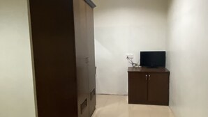 Een kamer met een kledingkast, een televisie op een dressoir en een betegelde vloer.