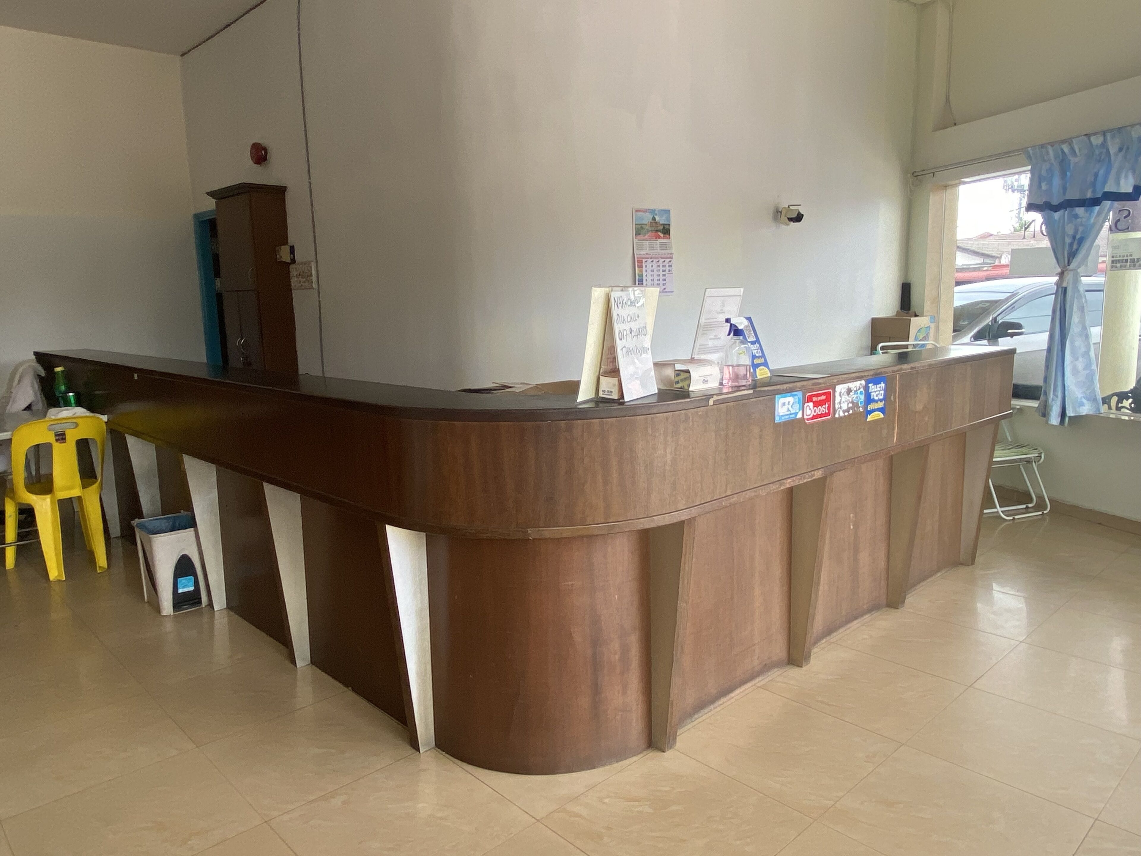 A reception desk with a calendar, a small trash bin, and a yellow chair.