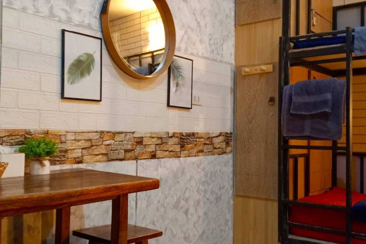 A bunk bed with a wooden ladder, a round mirror, and a small table with benches.