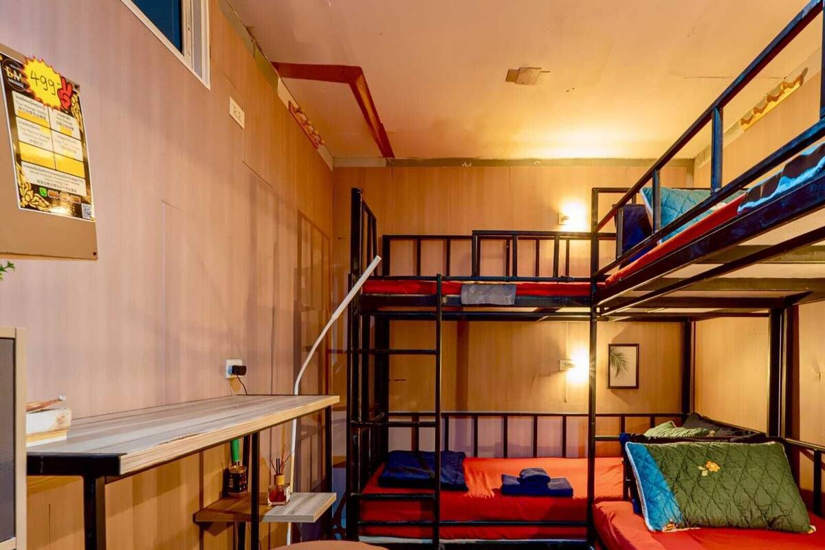 A dormitory room with bunk beds, a desk, and a chair.