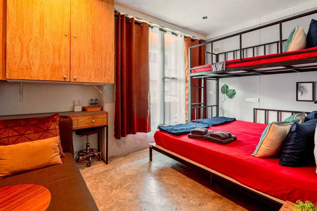 A compact room with a bunk bed, a desk, and a chair.