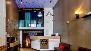 A reception area with a massage room sign, a reception desk, a sofa, and a wall with a map. - BM Loft On Nut & Massage (Bangkok)
