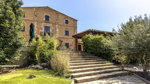 A stone building with a staircase leading to a covered entrance.