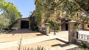 A courtyard with a stone gate, a paved entrance, and a building with a dark entrance door.