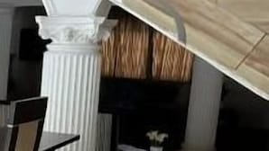 Een trap met een modern ontwerp, leidend naar een kamer met een open haard en een eethoek met een tafel en stoelen.