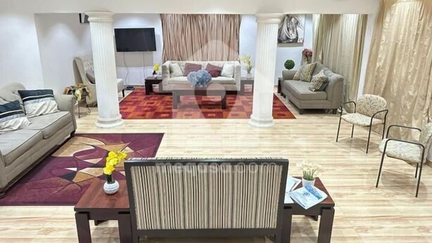 Een moderne woonkamer met een bank, een salontafel en een aan de muur bevestigde televisie.