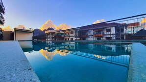 A modern building with a pool reflecting the sky and clouds. - Oudomsin VangVieng Hotel (Vang Vieng)