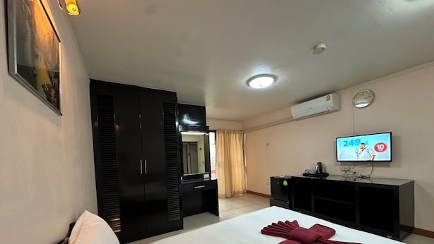 Una habitación de hotel con cama, armario, televisor y espejo.