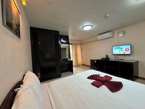 Una habitación de hotel con cama, armario, televisor y espejo.