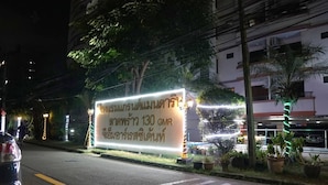 Un letrero bien iluminado con texto tailandés, que indica un hotel con 130 habitaciones.