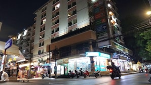 Un edificio de varios pisos con letreros iluminados y una tienda en la planta baja.