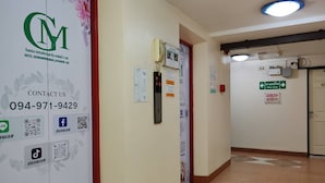 Pasillo de hotel con letrero de bienvenida, información de contacto y señalización de salidas de emergencia.