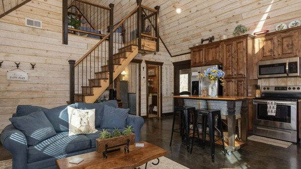 Un salon chaleureux avec un canapé bleu, une table basse en bois et un escalier menant à un niveau supérieur.