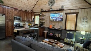 Une cuisine chaleureuse avec des meubles en bois, un four à micro-ondes et un coin repas comprenant un canapé et un téléviseur.