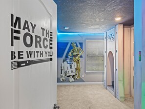 A hallway with Star Wars-themed decorations, including a wall with 'MAY THE FORCE BE WITH YOU' and a ceiling resembling a starry sky. - Your Dream Getaway in Kissimmee near Disney, FL. (Kissimmee)