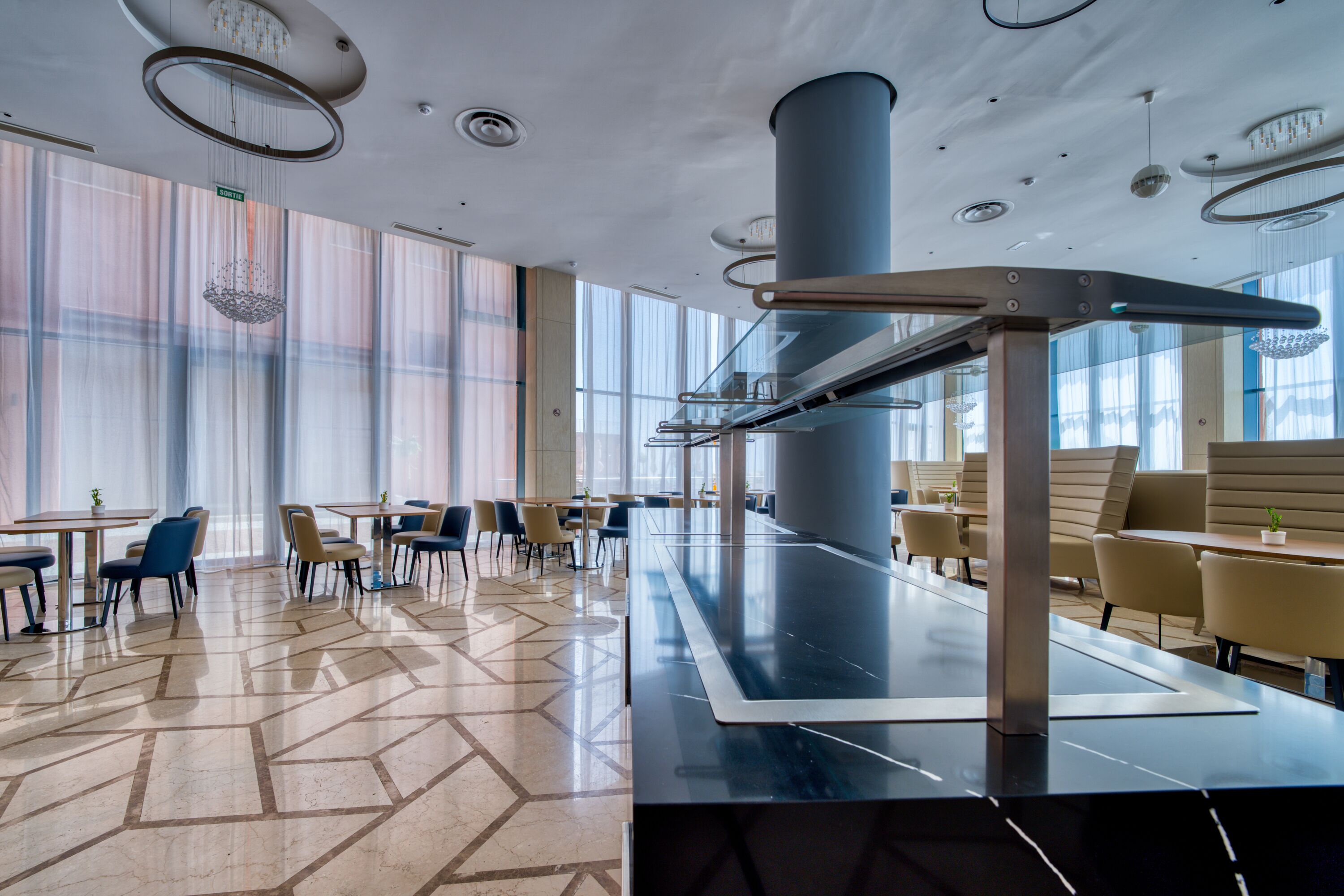 A modern dining area with a long table, chairs, and a central column.