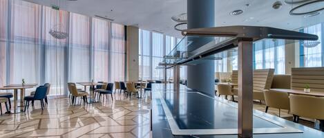 A modern dining area with a long table, chairs, and a central column.