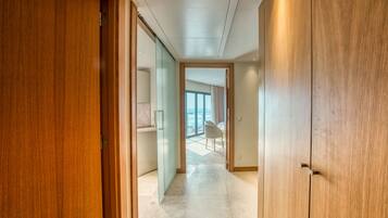 Passadís amb portes de fusta i vista a una habitació amb una finestra gran i una cadira.