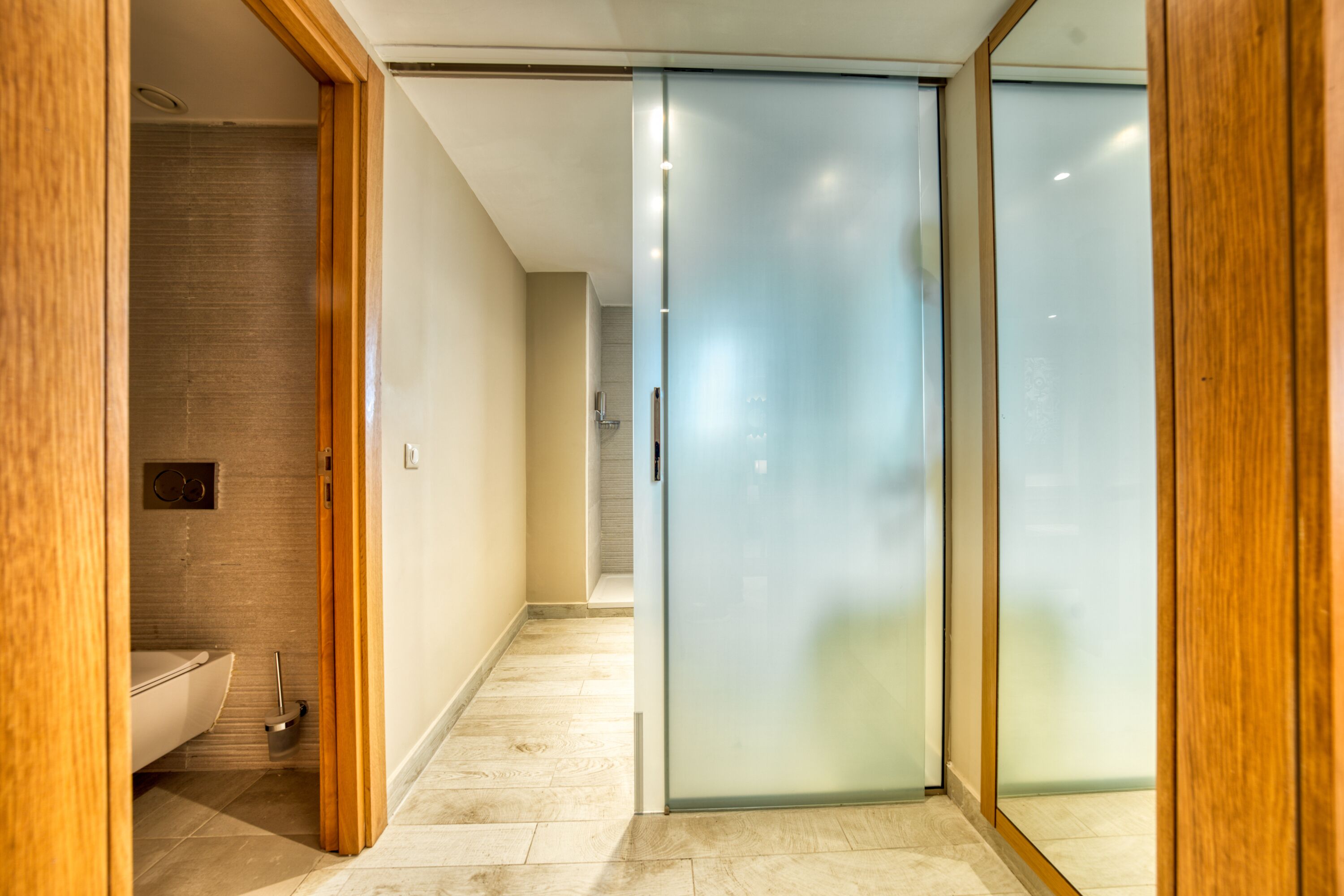 A modern bathroom with a toilet, bidet, and a glass shower enclosure.
