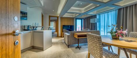 A modern hotel room with a kitchen, dining area, and a sofa.