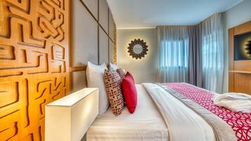 Habitación de hotel con cama, espejo en la pared y ventana con cortinas.