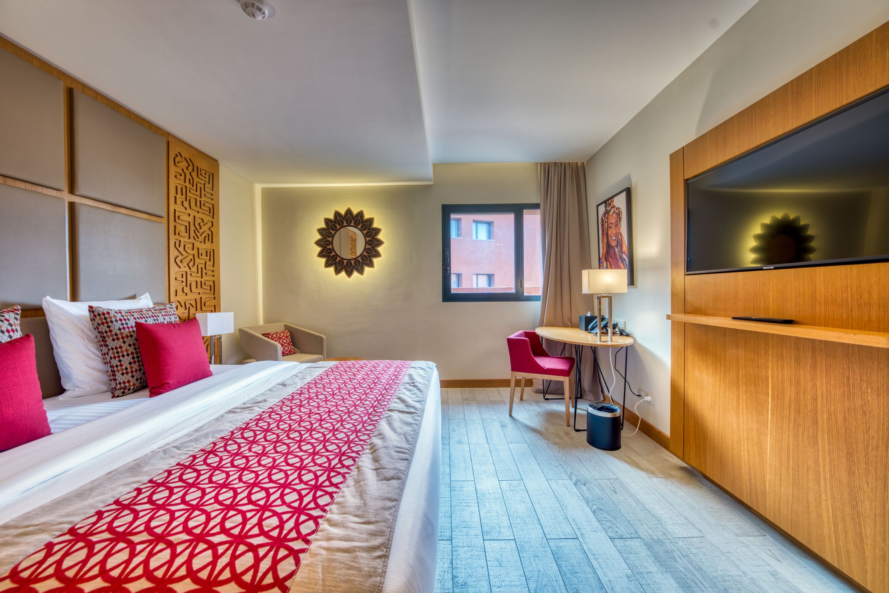 Een hotelkamer met een groot bed, een bureau, een televisie en uitzicht op het gebouw.