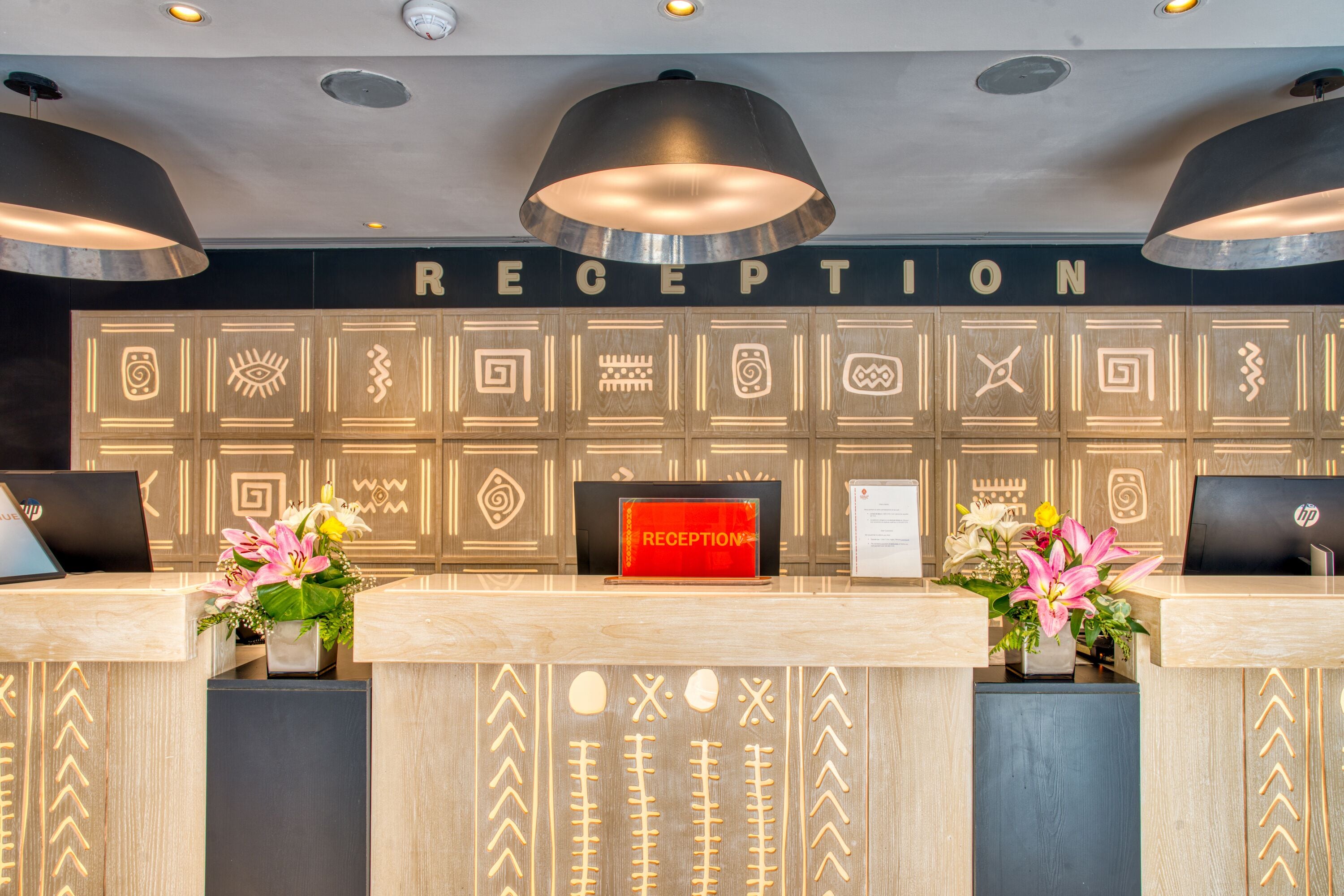 A reception desk with a 'RECEPTION' sign, two laptops, and decorative panels with geometric patterns.
