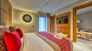 A modern hotel room with a large bed, a TV, and a wooden wardrobe.