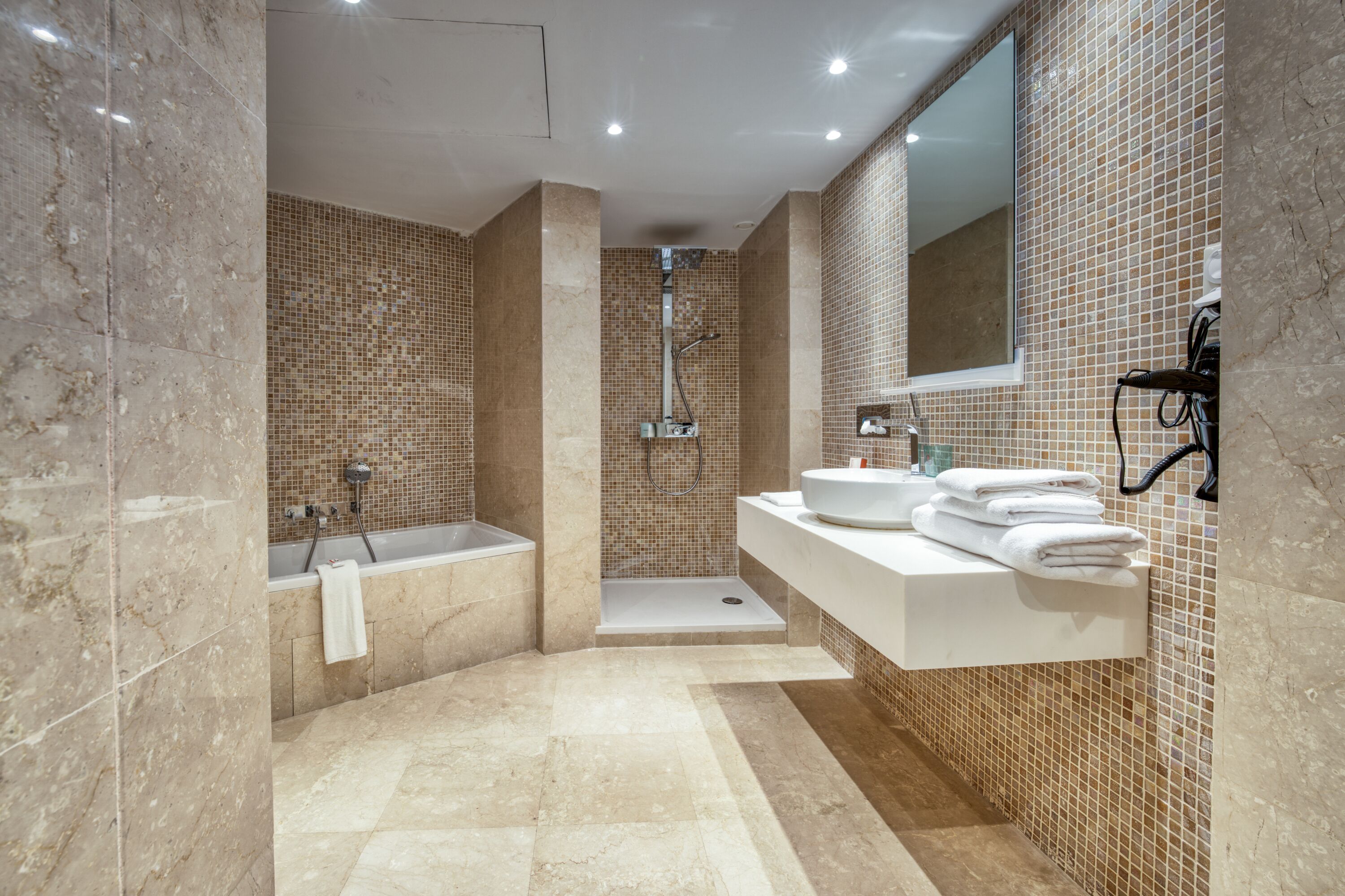 A modern bathroom with a bathtub, shower, and vanity.