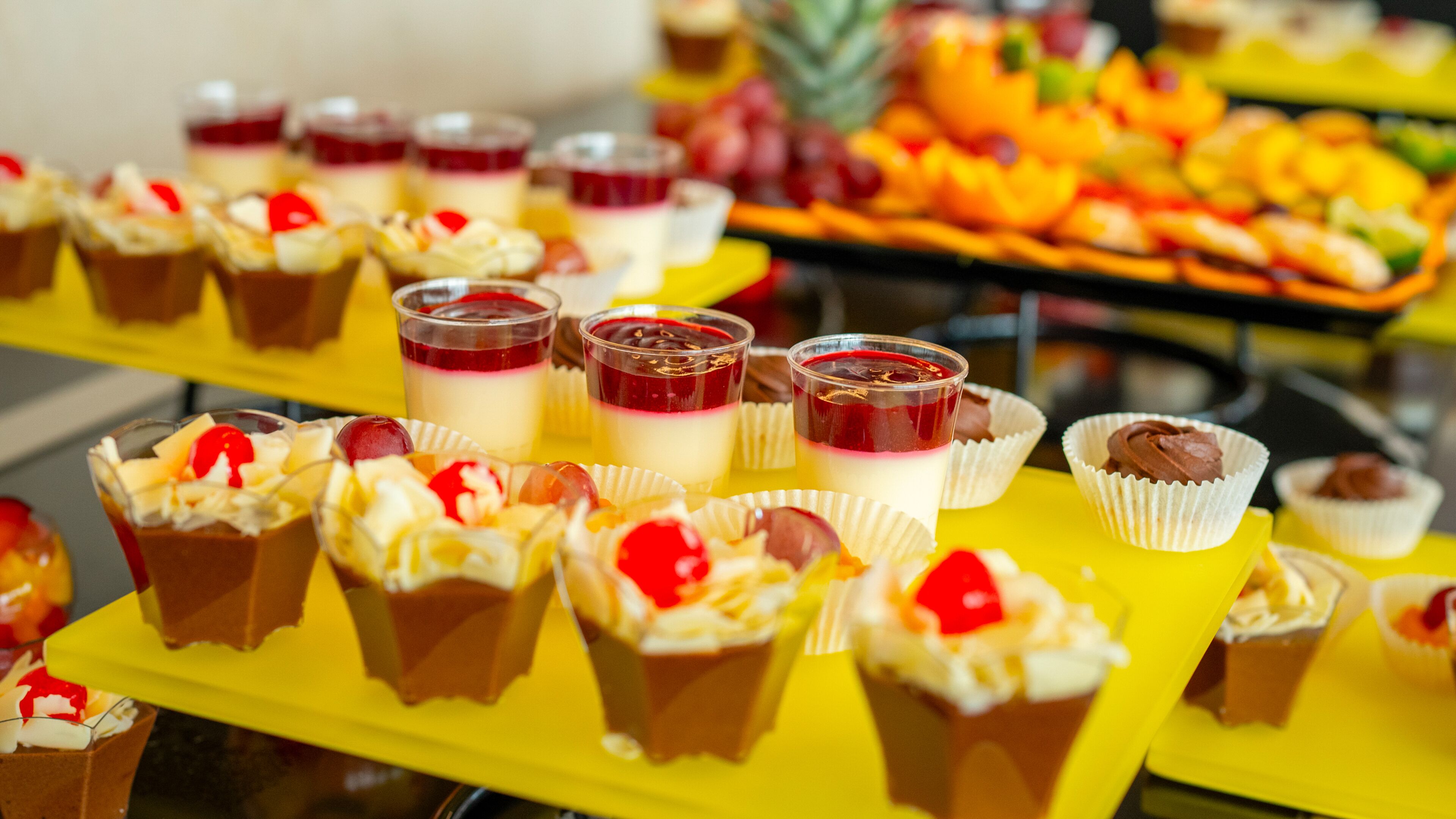 A buffet with various desserts including cupcakes and fruit arrangements.