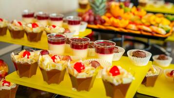 Un bufé con diversos postres, incluyendo cupcakes y arreglos de frutas.