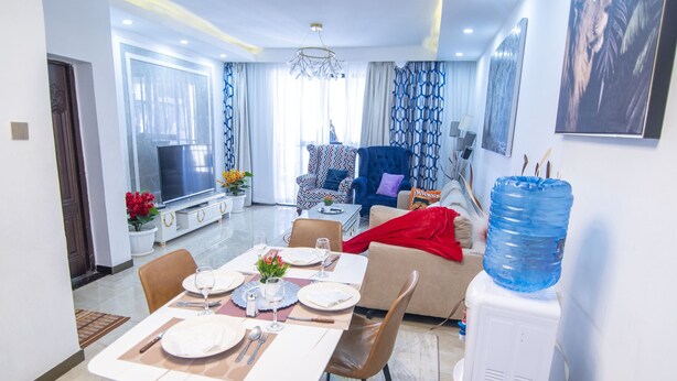 A modern living room with a dining area, a large water dispenser, and a TV.