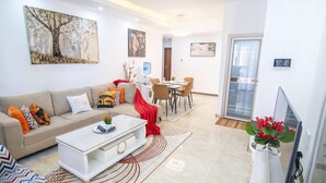 A modern living room with a sofa, coffee table, and a dining area with chairs and a table.
